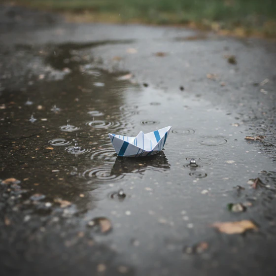 A paper boat on a rainy puddle, an example of a shot to make with Omni Flash in Pictory