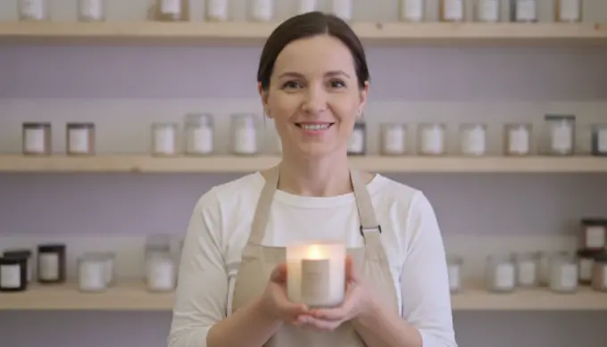 A candle shop owner holding a candle in a product video that uses AI-generated scenes