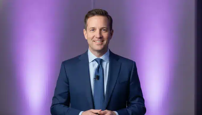 A conference host on a stage in a summary video made from a transcribed panel talk