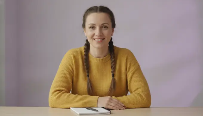 A help center writer smiling at her desk, with a help article turned into a how-to video by an AI video agent