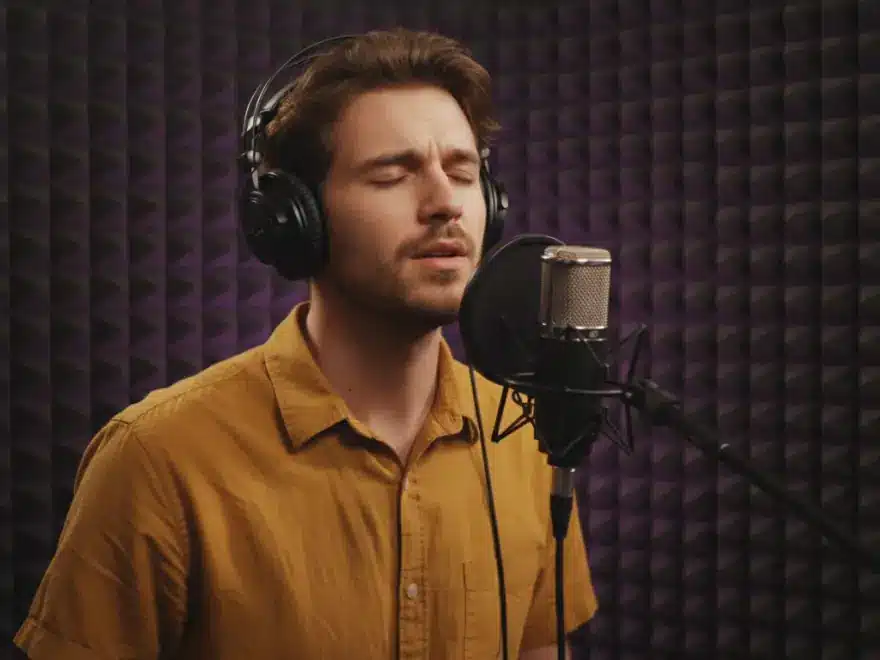 Indie artist singing into a studio microphone in a music video with his lyrics shown as captions