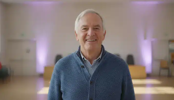 A nonprofit volunteer coordinator in a community hall in a Facebook video about an event