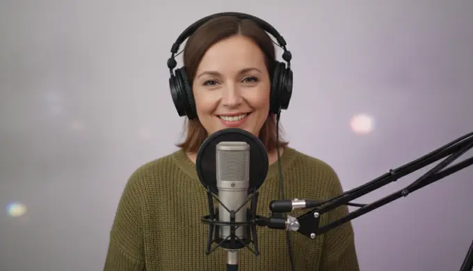 A podcast host at her microphone in a video made from her show audio