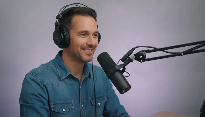 A podcast host at his microphone in a video intro for his show
