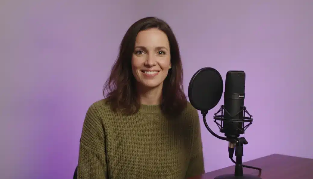 A podcast host smiling at the camera beside her microphone, with her recording turned into text by Pictory