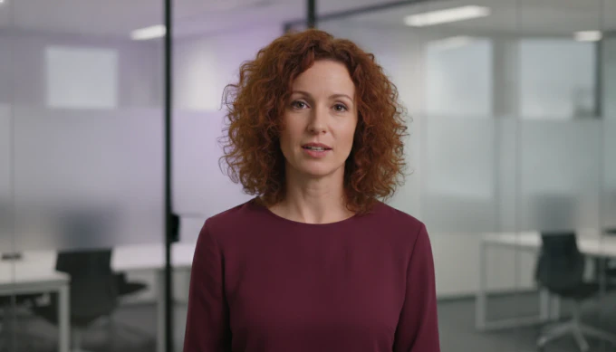A sales representative delivering a follow-up message as an AI avatar in a glass-walled office