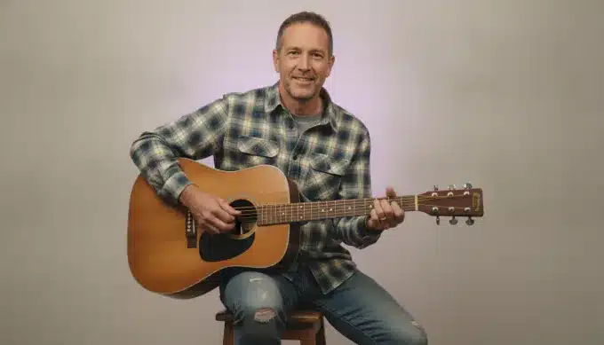 A songwriter with his acoustic guitar in a lyric video for his new single