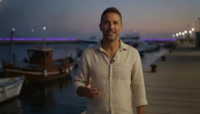 A travel creator on a harbor walkway in a video with AI captions from Pictory