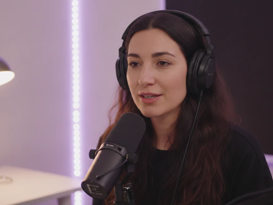 Woman in headphones speaking into a microphone to record a clean sample for her voice clone